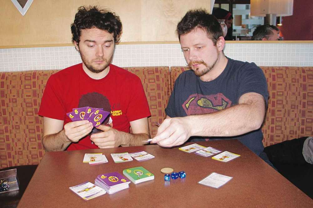Photo by Jared Story
Will O’Donnell (left) and Bart Rucinski play the card game they created, Surplus of Popes.