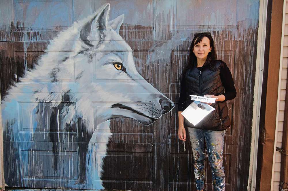 Alana Trachenko
Kal Barteski stands beside a mural of an Arctic wolf in her back lane. She’s been working on pieces of Arctic animals since returning from a mural festival in Churchill.