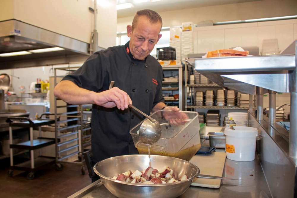 Canstar file photo by Justin Luschinski
Diversity Foods executive chef Kelly Andreas, pouring some dressing on potatoes at Pangea’s Kitchen.