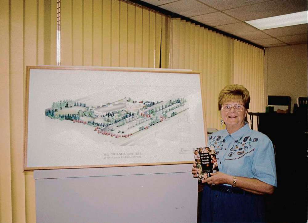 Olga Fuga is pictured beside the Wellness Institute’s architecture drawing in an undated photo.