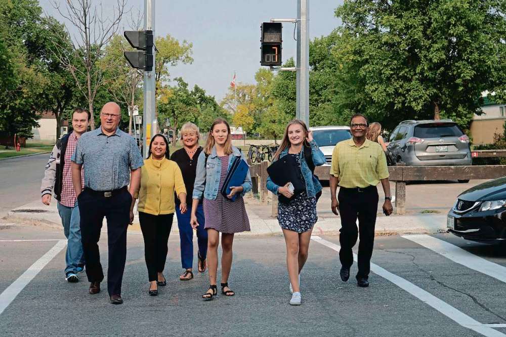 Photo by Ligia Braidotti
Seven Oaks Met School graduate James Toker, Garden City Collegiate principal Tony Kreml, Old Kildonan ward Coun. Devi Sharma, Garden City Collegiate vice principal Missy Penner, student council vice president Victoria Dias, student council president Amelia Kacperkiewicz, and Seven Oaks School Division board of trustees chairman Derek Dabee walk safely with the new set of traffic control lights installed at the intersection of Jefferson Avenue and Sinclair Street.
