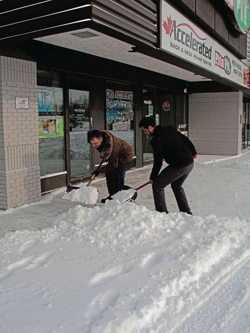 Tony Zerucha
There is a right way and a wronng way to shovel snow. Melnyk (left) demonstrates the wrong way while Gill employs proper technique by lifting with his knees.