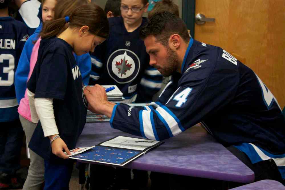 Winnipeg Jets defenceman Zach Bogosian signs a young fan's shirt at Princess Margaret School on Feb. 25. Bogosian and centre Mark Scheifele attended the I Love to Read Month event through the team's Reading Takes Flight program.