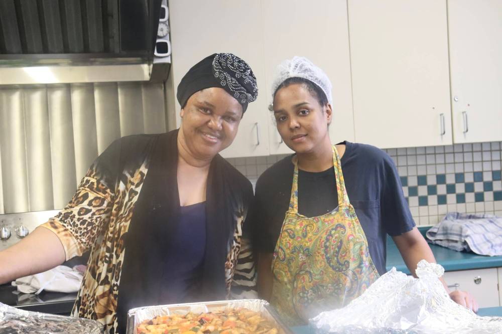 Photo by Emma Honeybun
                                Ubaida Dramani training a younger volunteer, Tsion, in the kitchen at Acorn Family Place.