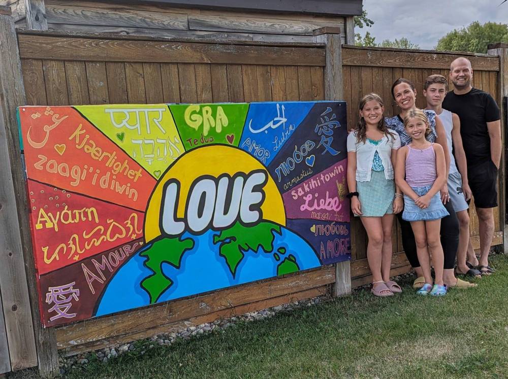 Photo by Sandy Nemeth
Ryan Loeppky (far right) poses with his message of love, alongside his wife, Andrea, and kids Jonah, Zara and Annika.