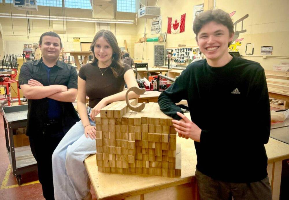 Photo by Adriano Magnifico
(From left) Christopher Grymaluk-Kirshner (VP of finance), Abby Parisian (VP of HR; and Emerson McFadyen (president) are pictured in the woods lab at Nelson McIntyre Collegiate with recycled wood used to make Cozie coasters.