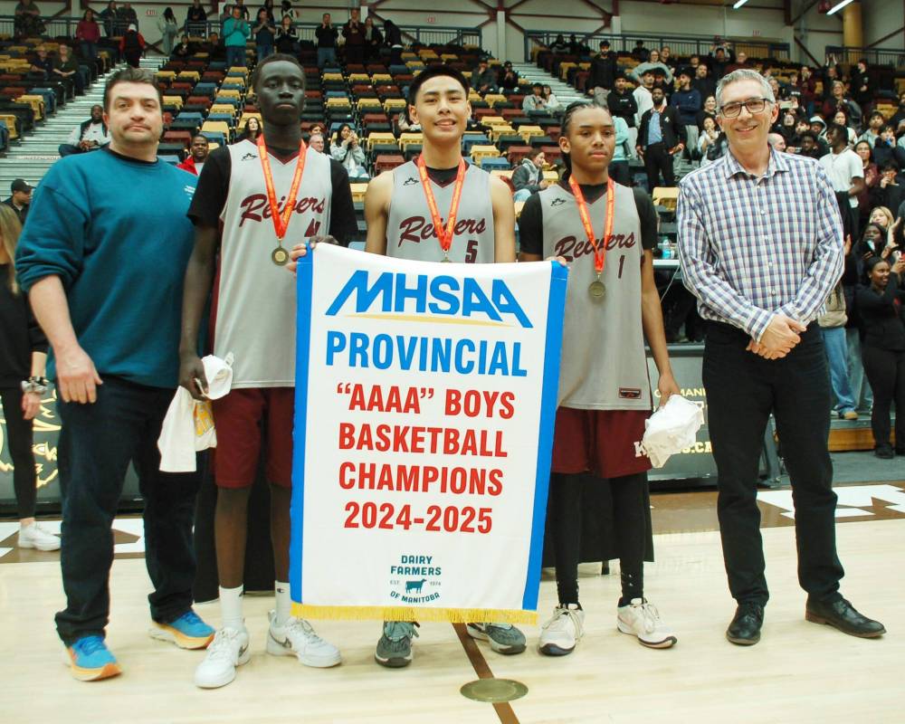 Lloyd Grenkow (left), representing tournament sponsor Dairy Farmers of Manitoba, and MHSAA president Jerret Long (right), presented Kildonan East captains Settimo Yugu, Adrian Lanoria and Rushawn Martin with the AAAA varsity boys championship banner.