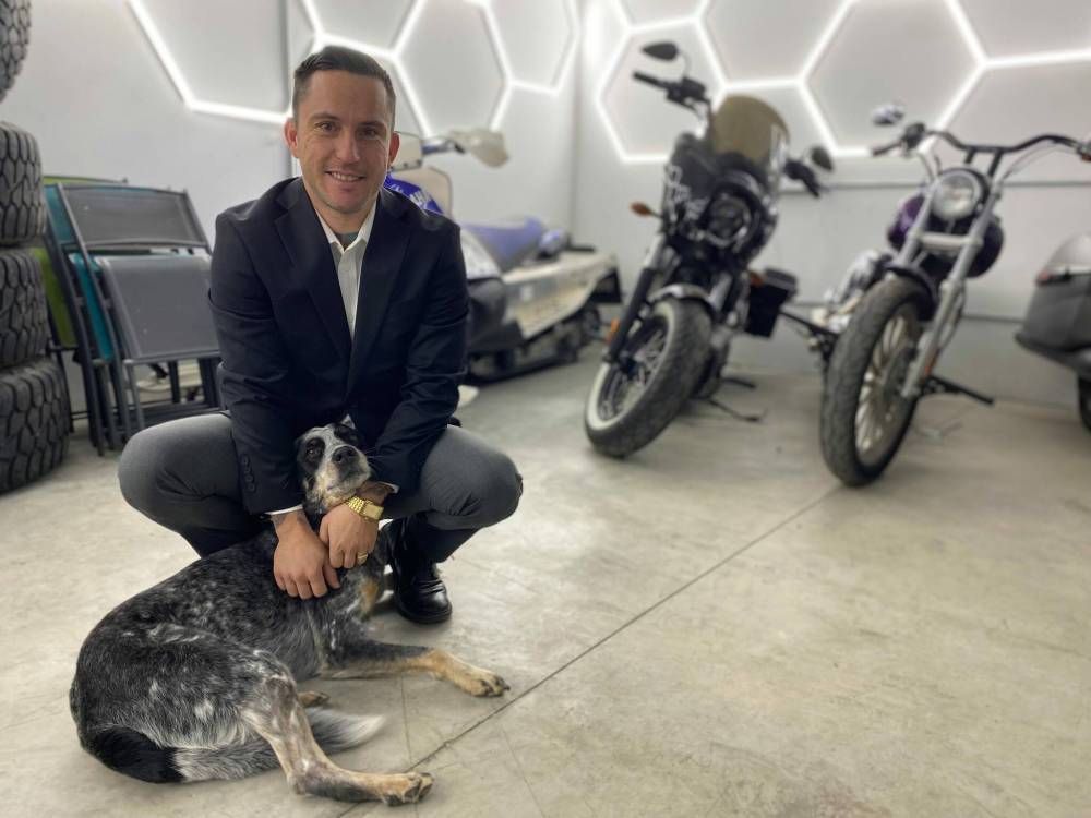 Photo by Sheldon Birnie
                                Ryan Buffie, pictured here with shop dog Theo, is the owner of Modern Motors (2071 Plessis Rd.). The shop, which has been operating since this summer, celebrated its official grand opening on Oct. 18.