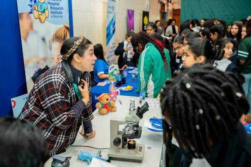 Supplied photo by George Photography
                                Azadeh Dalvand, a graduate student with the Children&rsquo;s Hospital Research Institute of Manitoba talks with students at the 2025 Women in STEM, AI & Innovation conference.