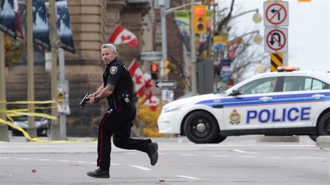 The RCMP and Canada's spy and border agencies reaped hundreds of millions of new dollars to fight terrorism in a federal budget that evoked the October killings of two Canadian soldiers in Saint-Jean-sur-Richelieu and Ottawa. An Ottawa police officer runs with his weapon drawn in Ottawa on Wednesday Oct.22, 2014. THE CANADIAN PRESS/Sean Kilpatrick