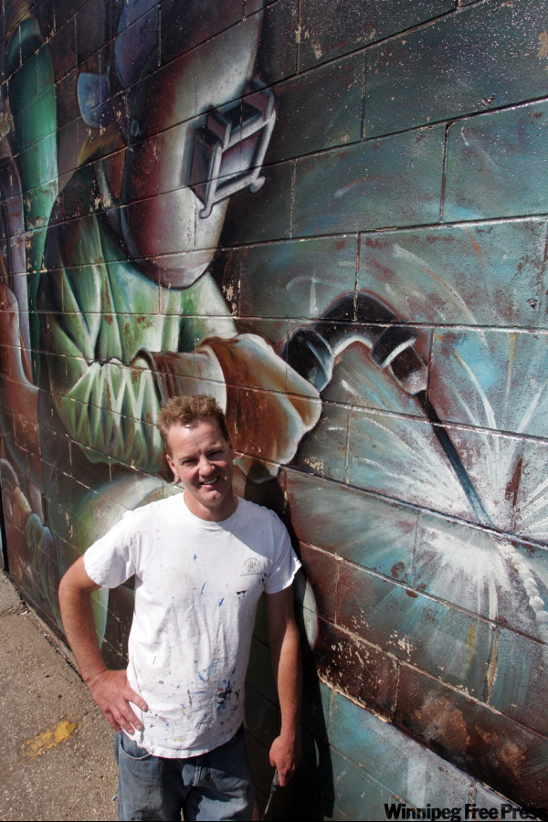 WAYNE.GLOWACKI@FREEPRESS.MB.CA
Artist Charles Johnston does repair work on his mural on the wall of United Association of Plumbers and Pipefitters building on Higgins Avenue.