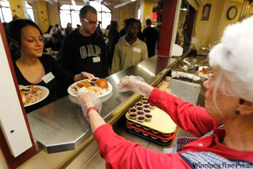 TREVOR HAGAN / WINNIPEG FREE PRESS
Volunteer Danielle Claridge receives food from Bobbie Holland at Siloam Mission on Friday. Between 500 and 700 people were expected to show up for the special Christmas Eve meal.