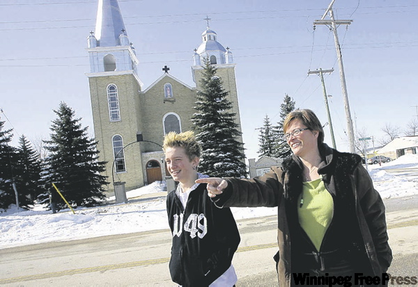MIKE DEAL / WINNIPEG FREE PRESS
Michelle Courcelles, with son Franky, points to their home across from the church.