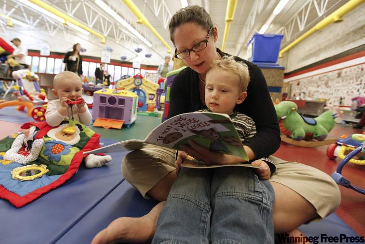 John Woods/Winnipeg Free Press
Bryanna Spina reads to her children Ilia, six months, and Mauro, 3, at Earl Grey Community Club last week. As with many women voters, family issues are important to her.