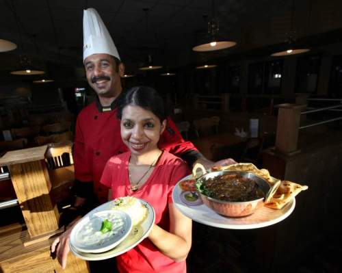 Phil Hossack / Winnipeg Free Press
Manoj Kumar, executive chef and owner at the Road House Eatery, poses with his wife Ambily Manoj holding a meal of South Indian chicken curry with home-made naan.