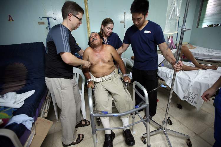 Phil Hossack / Winnipeg Free Press
The morning after knee surgery by the Operation Walk team in Managua, Juan Canda grimaces as he sinks into a chair after his first walk with physiotherapists Ian WIndle (left) Adrian Salonga. Both of Canda's knees were replaced during the surgery.