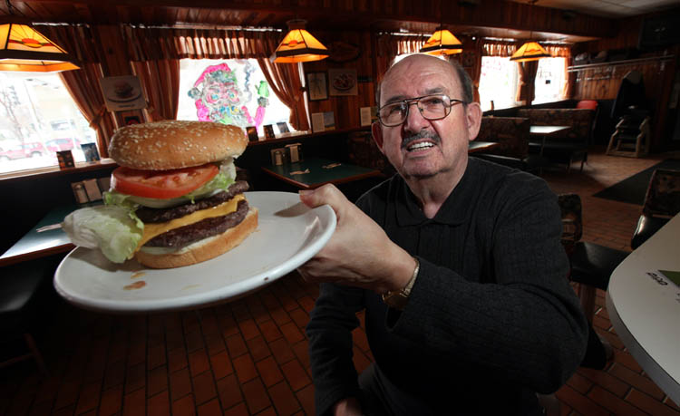 Phil Hossack / Winnipeg Free Press
John Ginakes shows off one of his signature burgers at the Thunderbird Restaurant.