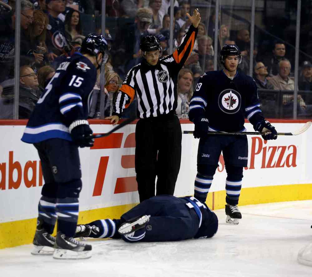 TREVOR HAGAN / WINNIPEG FREE PRESS
The referee summons trainers and medical personnel after Jacob Trouba crashed head-first into the boards during the second period of Friday night's game.