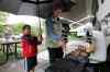 John Woods / Winnipeg Free Press
Kim Macaulay cooks under Tristan Szajewski's umbrella as his cousin, Ethan, looks on at the Birds Hill Park campsite Sunday.