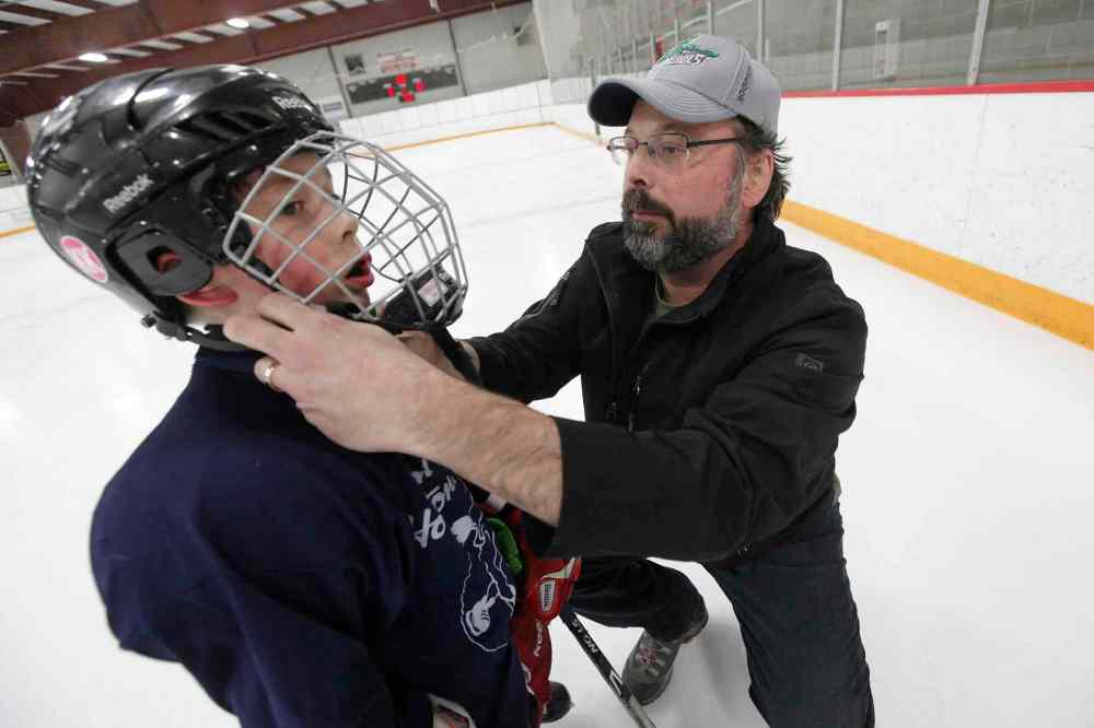 John Woods / Winnipeg Free Press
Troy Titterson puts a helmet on his son Finley at a spring hockey camp Gateway Arena Monday. A recent study shows hockey helmets are not good at protecting against concussions.