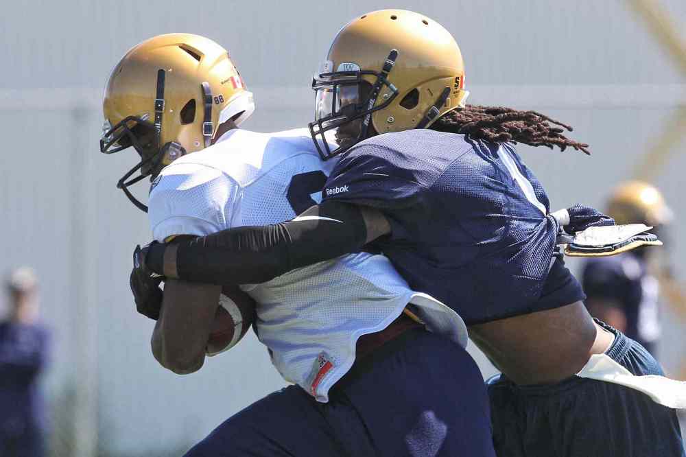 Mike Deal / Winnipeg Free Press
Jhomo Gordon (white jersey) is pulled down by Troy Stoudermire (1) during the first day of the Winnipeg Blue Bombers training camp.