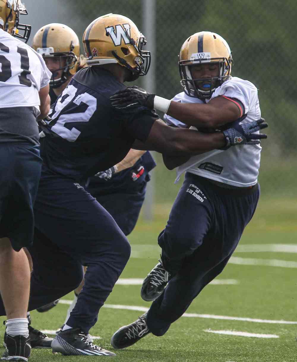 MIKE DEAL / WINNIPEG FREE PRESS FILES
Carlos Anderson (right) tries to carry the ball past Bryant Turner (92) during a training camp workout earlier this month.