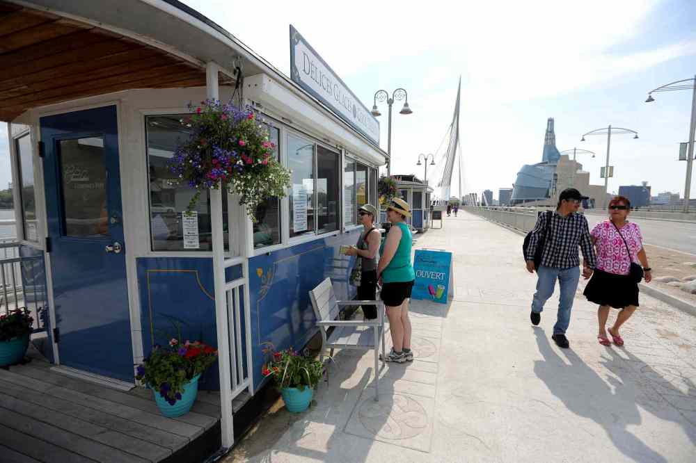 TREVOR HAGAN / WINNIPEG FREE PRESS
Teresa Bowerman and Val Gompf buy cool treats from one of three seasonal kiosks on Esplanade Riel designed to look like horse-drawn trams.