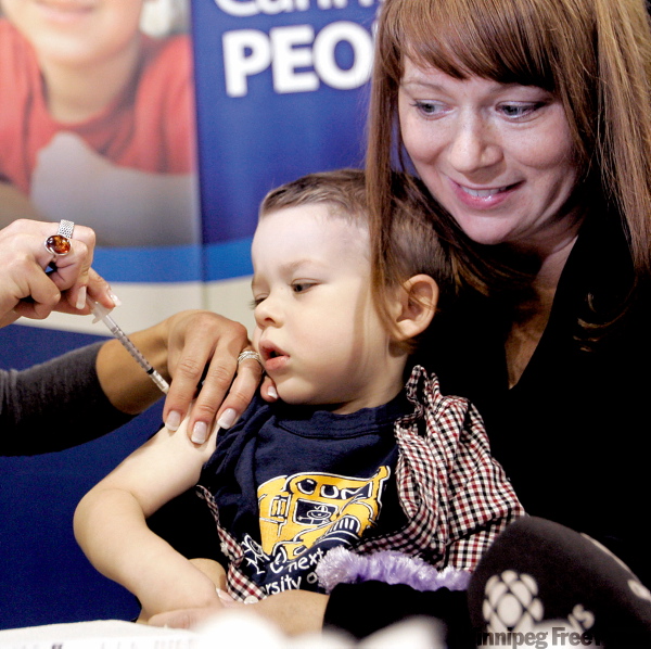 WAYNE.GLOWACKI@FREEPRESS.MB.CA
Easton Horbatiuk, with his mom, Tamara, puts on a brave face at the Franco-Manitoban Cultural Centre Monday. The three-year-old was one of 4,000 in Winnipeg who rolled up their sleeves on the first day of the province’s mass H1N1 immunization program.
