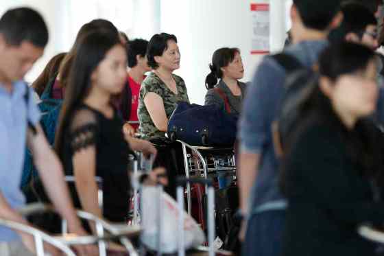 JOHN WOODS / WINNIPEG FREE PRESSJian Wyatt (centre) and other Air China passengers wait to check in to board a plane out of Winnipeg Sunday. Passengers from an Air China had to make an unscheduled stop in Winnipeg when their flight made an emergency landing Saturday night.