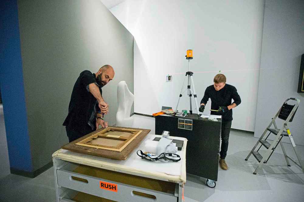 Head of museum services Radovan Radulovic (left) and preparator Serge Saurette hang pieces.