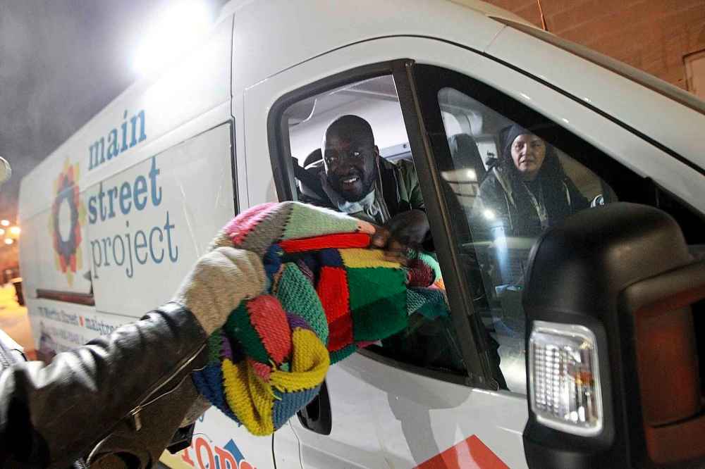 PHIL HOSSACK / WINNIPEG FREE PRESS
Emmanuael Olatubosun hands out a wool blanket to a man living on the streets Thursday night.