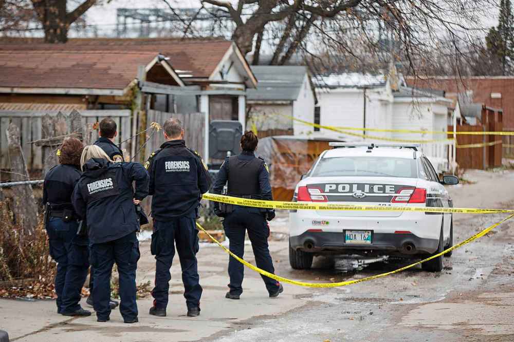 Winnipeg police officers examine the back lane between Arlington and Burnell streets, retracing the steps of Matthew Allan Sutherland, 28, who was stabbed to death last week. (Mike Deal / Winnipeg Free Press files)