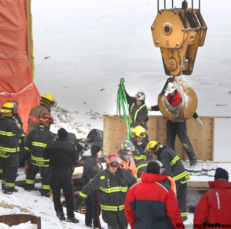 Wayne Glowacki / Winnipeg Free Press
Construction workers use their crane to raise an overturned vehicle that crashed through a railing on the Disraeli Bridge.