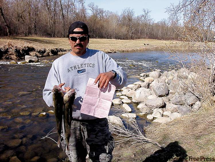 BILL REDEKOP / WINNIPEG FREE PRESS
Gilbert Sinclair of Ebb and Flow First Nation holds a citation for fishing during the ban in one hand and the two pickerel he caught on Wednesday.
