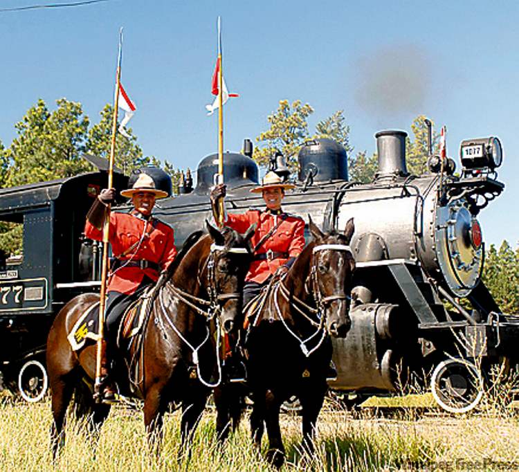 Vintage train locomotive 1077 gets an RCMP escort near the Fort Steele Heritage Townsite grounds.