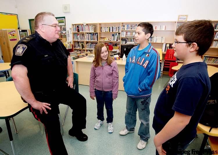 Ken Gigliotti/ Winnipeg Free Press
Const. Scott Wiley visits Inkster School and chats with Grade 6 students (from left) Faith Gallaugher, Giuseppe Cisternino and Brenden Heide.