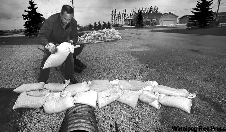 PHIL.HOSSACK@FREEPRESS.MB.CA
James Feagan recycles sandbags he and neighbours used to build dikes around their properties to protect their homes against a flood that never came.