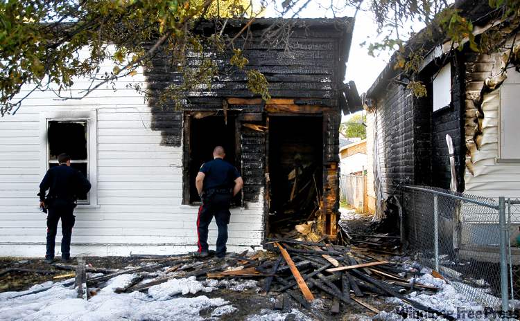 WAYNE GLOWACKI / WINNIPEG FREE PRESS
Winnipeg police officers inspect damage caused by Monday�s house fire in the 700 block of Aberdeen Avenue. The blaze spread to the neighbouring property.
