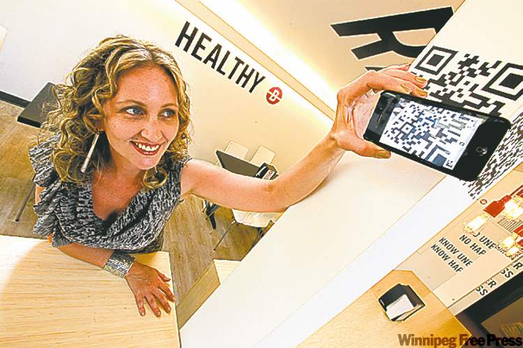 John Woods/Winnipeg Free Press
Erica Glasier, a Winnipeg marketer and blogger, scans a QR code at Unburger in Osborne Village. Glasier says the technology can be hit or miss and simple is better.