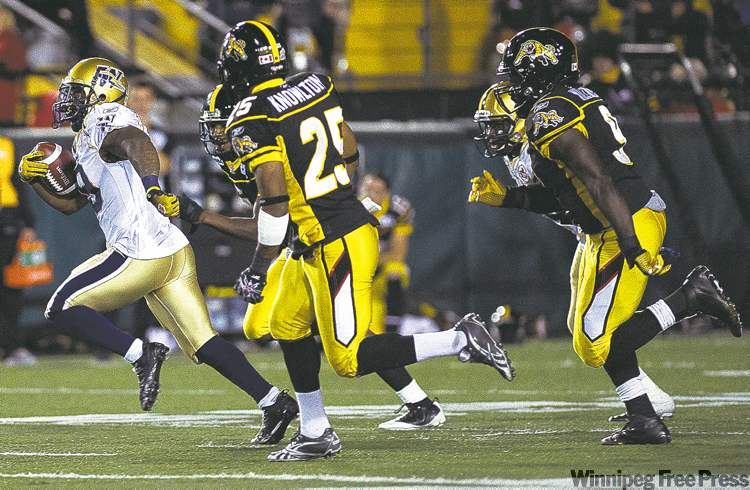 Nathan Denette / the canadian press
Winnipeg running back Chris Garrett (left) eludes a group of would-be Hamilton tacklers Friday.