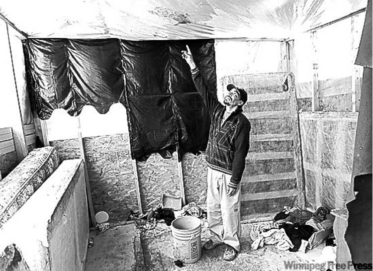 Geordie Rae Jr. checks for leaks in the plastic roofing over his family's temporary housing.