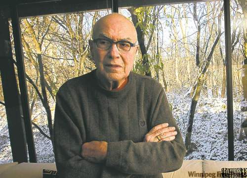 Dr. Jack Fainman in his home in St.Vital.  Behind him is the location outside where the gunman shot him.