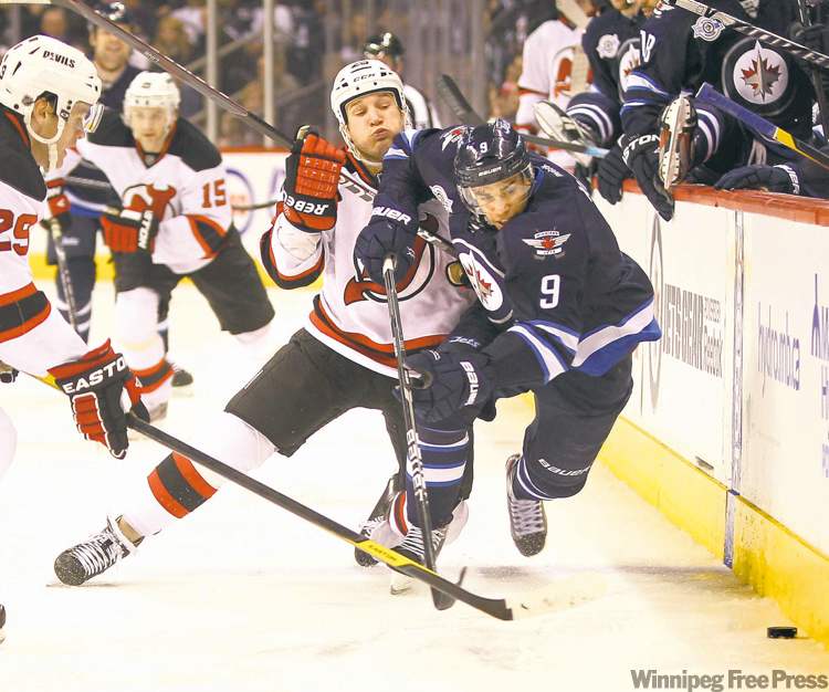 Jets' Evander Kane fights to get to the puck as Devils' Cam Janssen pushes him to the ice in the second period Saturday afternoon at the MTS Centre.