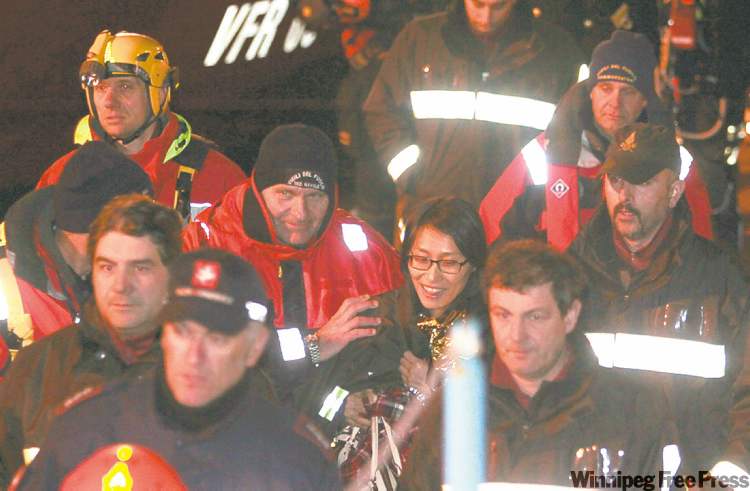 CP
GREGORIO BORGIA / THE ASSOCIATED PRESS
A South Korean woman rescued from her cabin late Saturday leaves the ship accompanied by firefighters. She and her husband, who was also rescued, were on their honeymoon cruise.