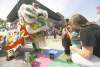 Members of The Lion Dance, performed by the Ching Wu Athletic Association, stop to meet Daphne Young, her son Franco Young, 19 months, and Heather Millar, during the Chinatown Street Festival Saturday.