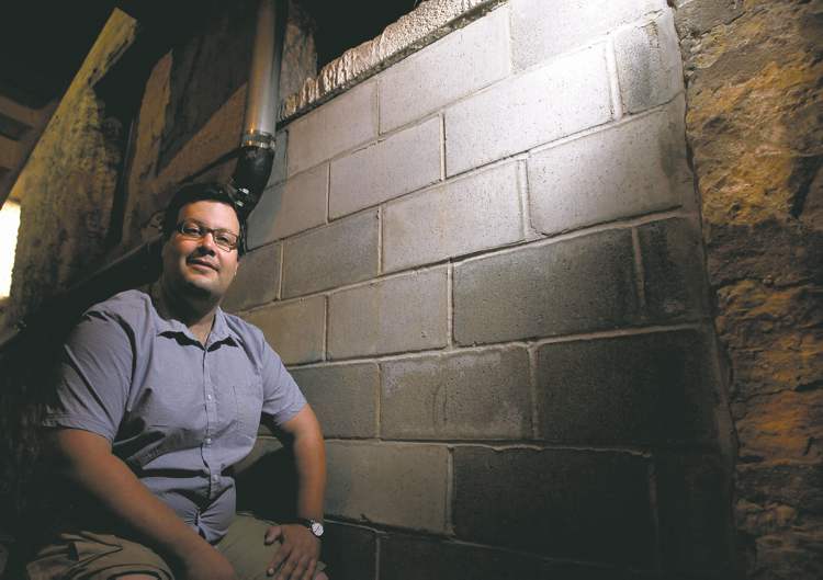 WAYNE GLOWACKI / WINNIPEG FREE PRESS
Ben Hnatiw, property manager of the Prairie Housing Co-op, sits by the bricked-up entrance of a 100-year-old Winnipeg tunnel.