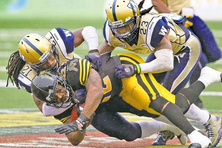 Chris Young / The Canadian Press
Bombers Alex Suber (left) and Jonathan Hefney wrap up Hamilton's Avon Cobourne Saturday. Hefney, a free agent to be, says he will stay loyal to the Blue & Gold if plans down south don't work out.