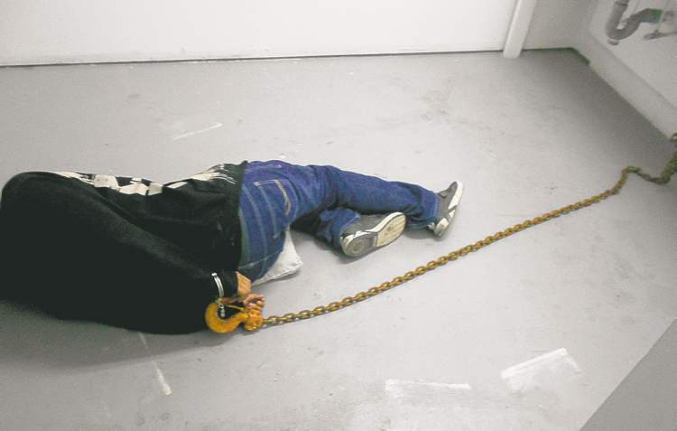 Manitoba Keewatinowi Okimakanak / Winnipeg free press archives
A Northlands Denesuline First Nation man is held in a dressing room in Lac Brochet's community arena in August.