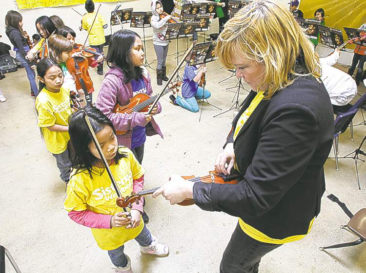 Mike Deal / Winnipeg Free Press
AJ Rosaldo, 8, has her violin tuned by Sistema Winnipeg teacher Barbra Hamilton before Elwick Community School students perform for Winnipeg Harvest volunteers Monday.