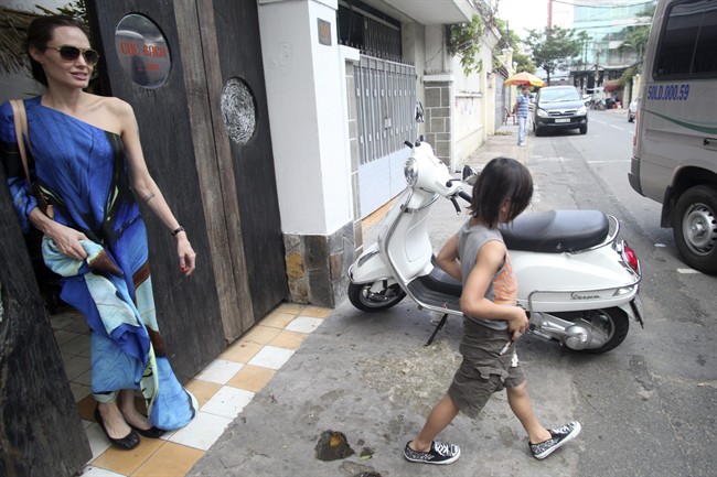 American actress Angelina Jolie, left, and her adopted son Pax Thien leave a Vietnamese restaurant in Ho Chi Minh City, Vietnam, after lunch on Friday, Nov. 11, 2011. Hollywood power couple Jolie and Brad Pitt and their six children are on a visit to Vietnam, where Pax was born. (AP Photo/Na Son Nguyen)
